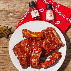 Thoughtfully pouring a mango-style sauce from a mini bottle onto grilled meat for glossy finish