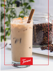 Torani 25.4 oz bottle next to a measuring cup showing scale and volume