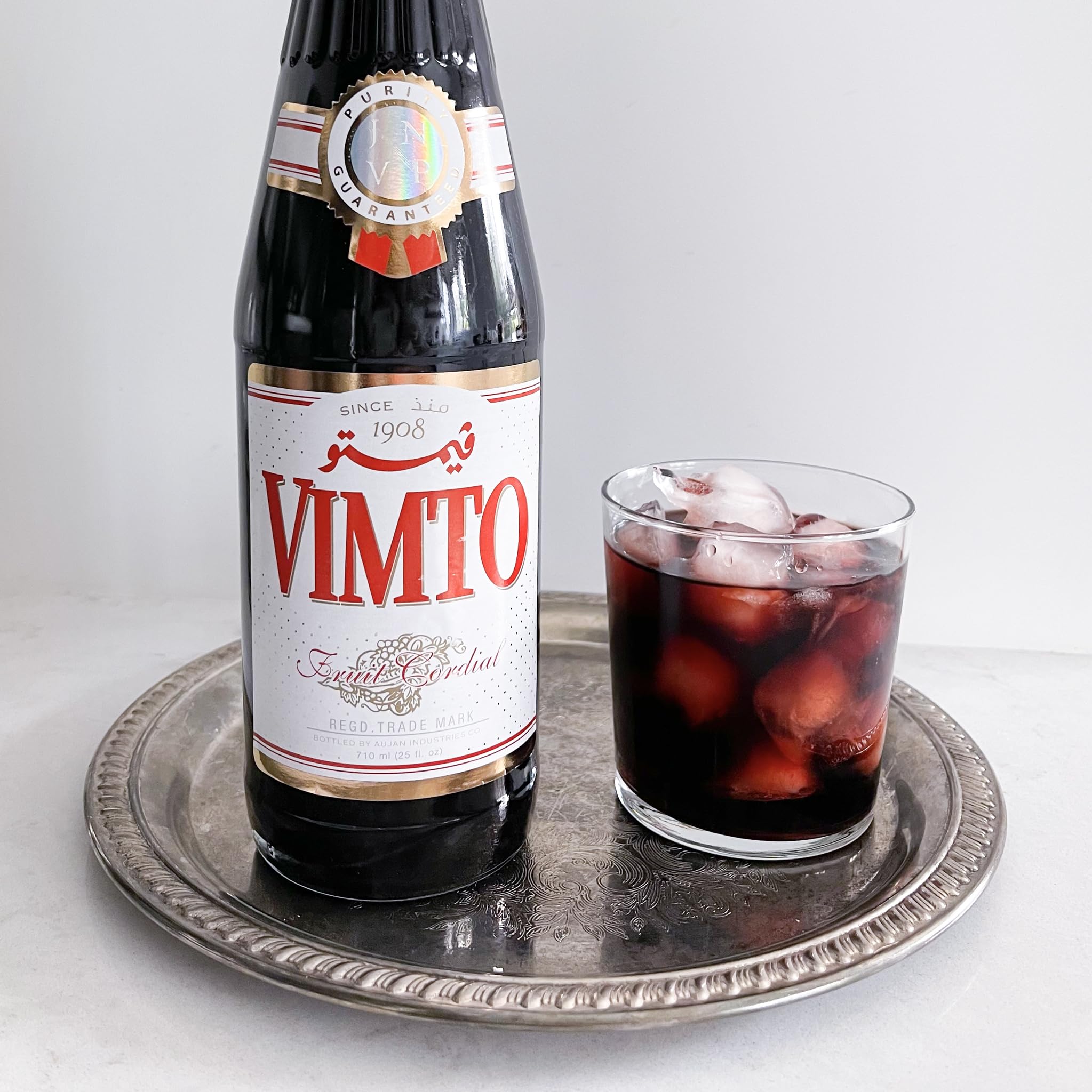 Vimto syrup pouring from bottle close-up showing rich texture for easy mixing